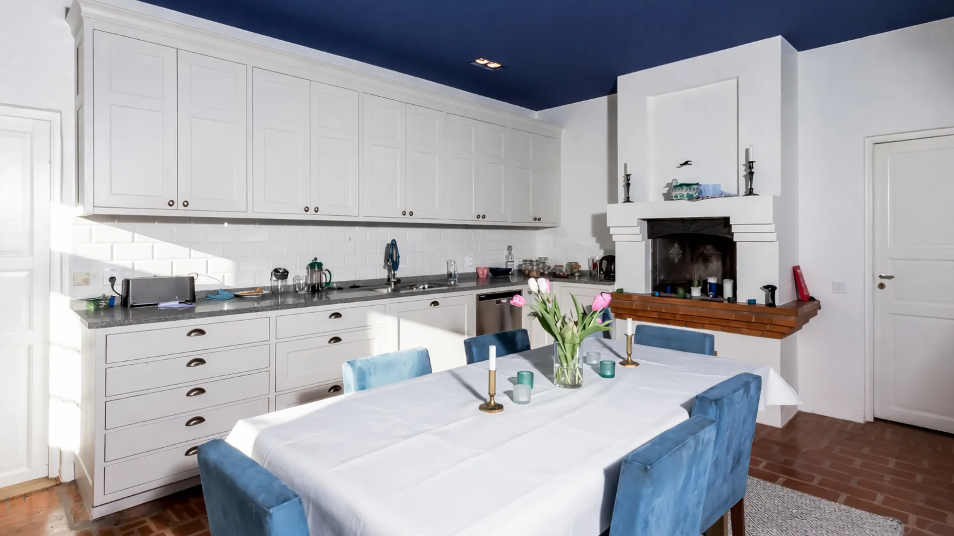 Country-style kitchen in Sweden with hand-painted framed cabinetry and stone countertops